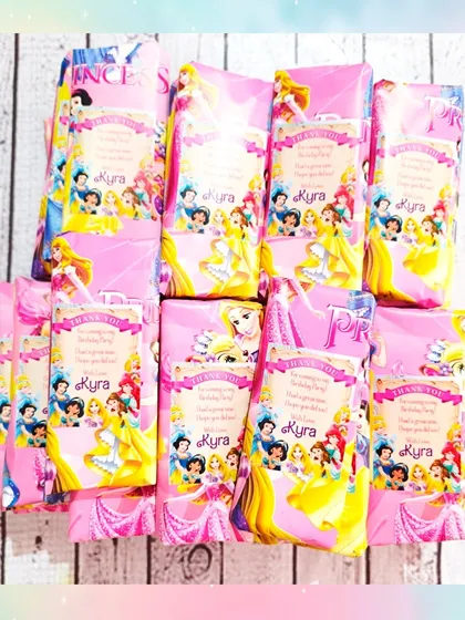 A batch of the DIY coloring bags wrapped in beautiful princess-themed paper with personalized "Thank You" tags for a guest named Kyra.