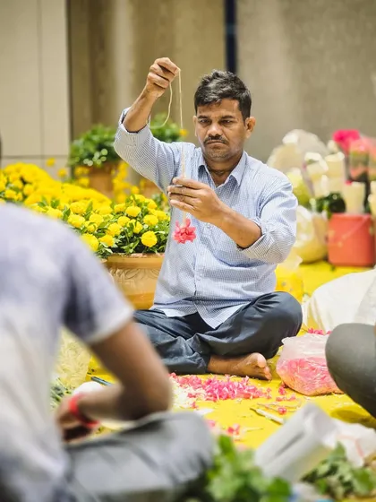 It’s the people behind the scenes that truly make an event. Here, one of our skilled artisans is carefully stringing fresh flowers, a craft that requires patience and precision.