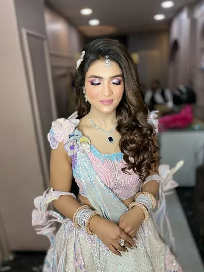 A gorgeous engagement bride in a unique pastel multi-colored lehenga. The makeup has soft pink and purple tones to match her outfit.
