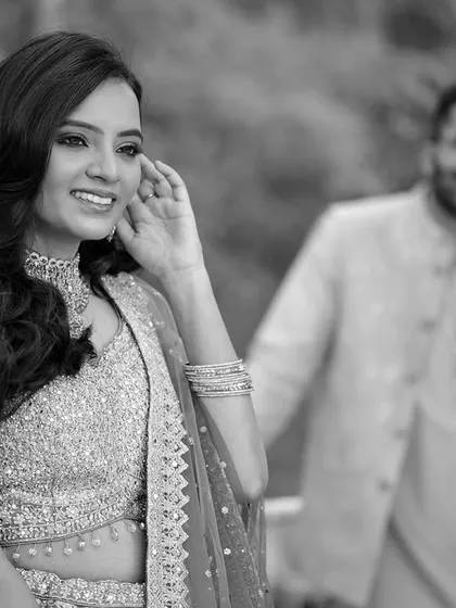An artistic black and white shot with the bride in focus and the groom softly blurred in the background.