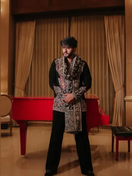 A client posing in a black Indo-Western outfit featuring a heavily embroidered stole. This look combines a simple base with a statement accessory for a unique and stylish effect.