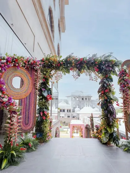 An entrance adorned with traditional woven art and lush floral arrangements, offering a unique and artistic welcome.