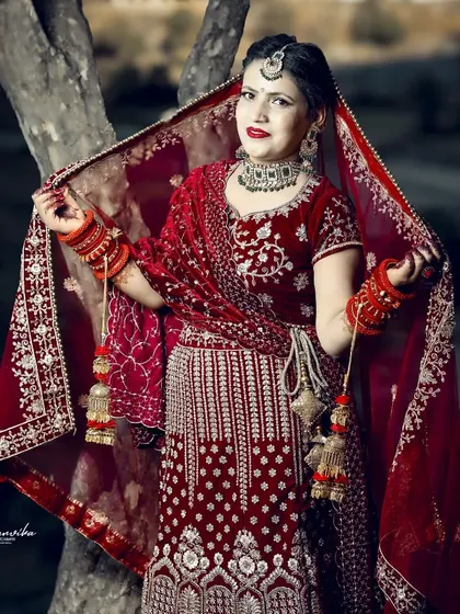 A bride gracefully holding her dupatta. This pose creates a classic and elegant silhouette, perfect for a timeless bridal album.
