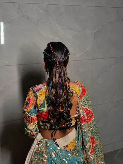 A fun and festive ponytail for Navratri, with colorful threads braided into the hair for a playful touch.