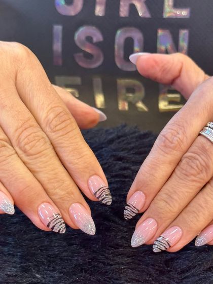 A chic and modern design combining glitter and linework. This set uses a sheer pink base with some nails fully coated in silver glitter and others featuring thin, black zebra-like stripes.