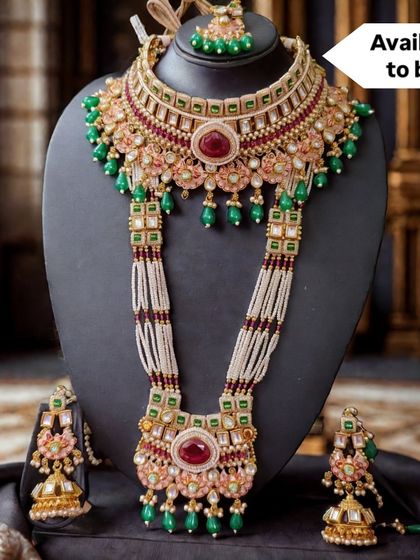 This grand bridal set with red and green accents is part of my exclusive 'Amulya Dharohar' line. It features a choker, a long necklace with pearl strands, and matching earrings, designed for the bride who wants to own her legacy.
