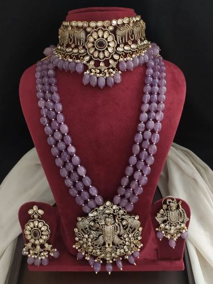 This lavender beaded jewelry set features a choker with elephant motifs and a long necklace with a large deity pendant. It's a majestic set perfect for a grand bridal look.