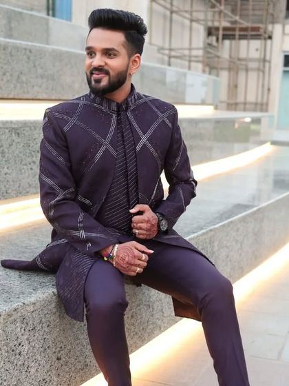 The groom seated in his purple open Indo-Western jacket. The hand and machine work creates a linear pattern that is both modern and elegant.