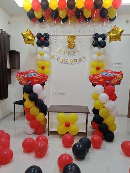 A Disney Cars themed 5th birthday party with Lightning McQueen foil balloons and balloon columns in red, yellow, and black.