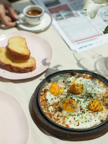 A breakfast scene featuring my sizzling shakshouka, served straight from the pan, alongside fresh bread and a cup of espresso.
