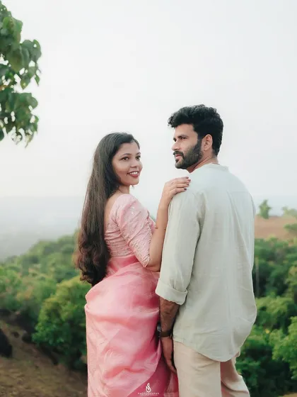 A lovely pose overlooking a valley of green hills. This shot combines an intimate moment with a grand, scenic landscape.