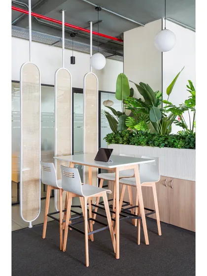 Another angle of the high-table setup, showing the hanging partitions and planter box that define the space. These elements add layers and visual interest to the open floor plan.