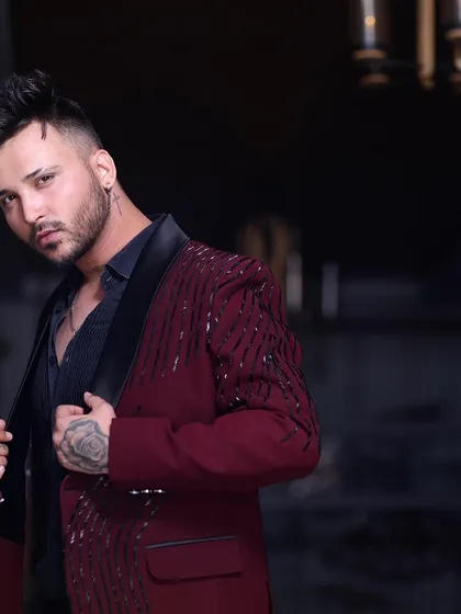 A closer look at the maroon tuxedo jacket, showing the detail of the sequin work and the sharp cut of the lapels.