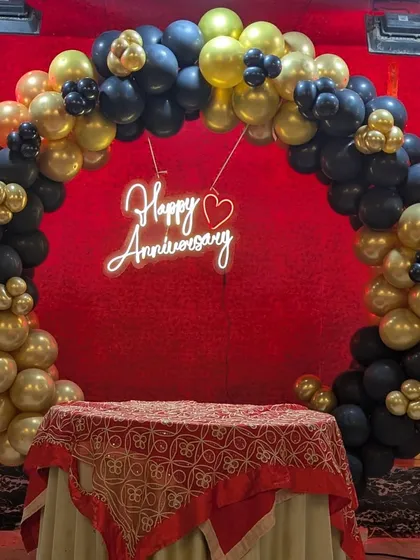 The circular black and gold balloon arch with a neon sign, set up perfectly behind the cake table.