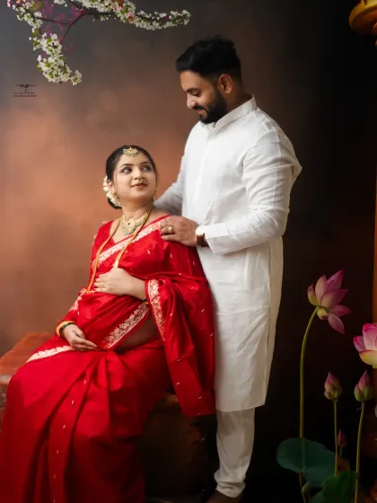 The couple shares a look of love in this beautifully composed traditional portrait. The scene is set with lotus flowers and classic props, adding to the artistic feel.