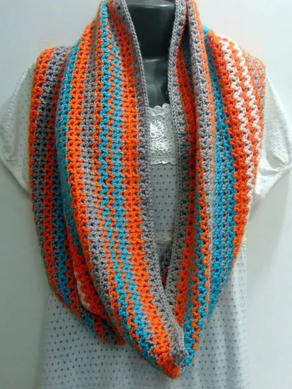 This V-stitch infinity scarf, or snood, is made with a simple stitch that creates a lovely, open texture. The color combination of grey, orange, and blue is bright and cheerful.