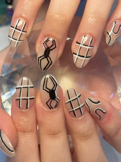 For those who love a bit of edge. This unique nail art features hand-drawn spiders, webs, and abstract lines on a neutral base for a cool, graphic look.