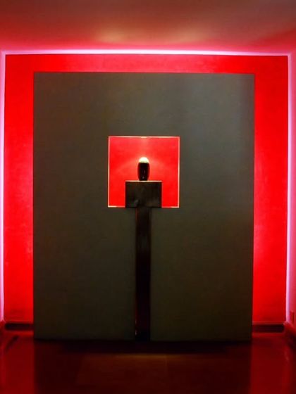 A dramatic entrance at the LMW Headquarters, where a central art piece is framed by glowing red light. This use of lighting and art creates a powerful and memorable threshold experience.