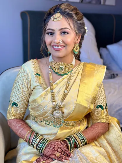 A bright, smiling portrait of the golden bride. Her makeup is flawless, with a focus on luminous skin and a smile that lights up the room.