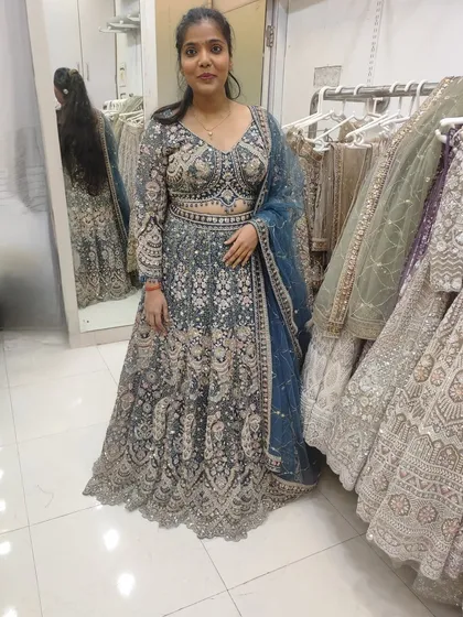 A client trying on a grey-blue lehenga in the store. The fit is perfect and she looks very happy.