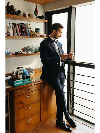 A classic groom portrait. Leaning against his desk by the window, he looks dapper and ready for the big day, with the soft light adding a touch of sophistication.