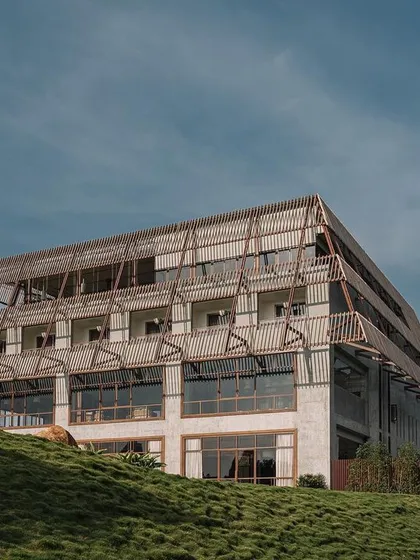 The Estates Club in Nandi Hills, a large structure whose mass is visually softened by an encompassing facade of wooden slats, allowing for views while creating a distinct form.