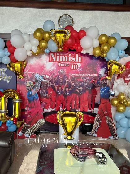 For the ultimate cricket fan, we designed this RCB-themed 10th birthday party. The decor features a backdrop with the RCB team, cutouts of star players, trophy props, and a balloon arch in the team's colors.