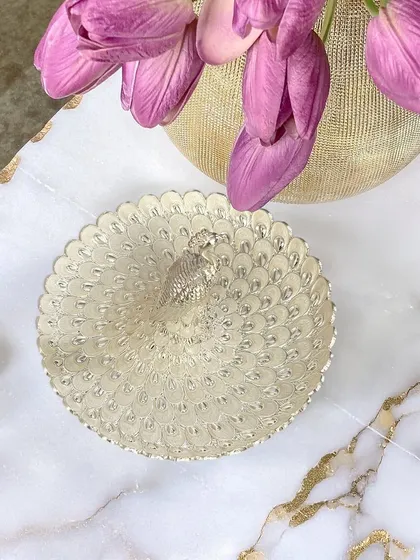 Styled on a marble surface, the detailed feather engravings of this silver peacock tray catch the light beautifully. It is a versatile piece that blends seamlessly with both modern and traditional decor.