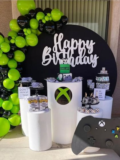 Level up your party with our video game theme. This Xbox-inspired setup features a black and neon green color scheme, a giant controller prop, and themed pedestals for snacks and the birthday cake.