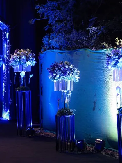 The pathway to the event was lined with these futuristic floral stands, combining metallic structures, crystal elements, and blooms under moody blue lighting.