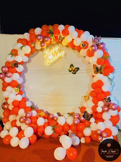A vibrant orange and white balloon ring with butterfly accents, a cheerful setup for any happy occasion like an anniversary.