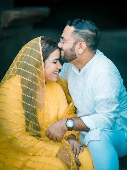 A sweet and candid moment from a pre-wedding shoot. The groom's gentle forehead kiss and the bride's happy smile are the focus of this intimate portrait.
