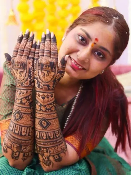 A joyful bride posing with her traditional elephant-themed mehendi, a popular choice for Indian weddings.