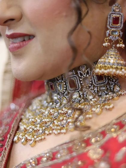 A detailed close-up of the bride's traditional jewelry. This shot focuses on the intricate design of her choker and jhumkas, an essential part of the complete bridal look.
