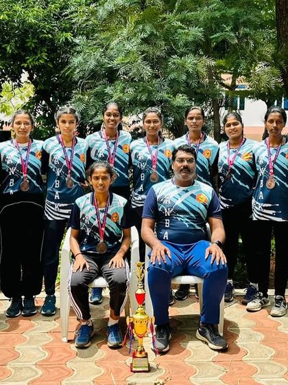 Our formidable girls' netball team posing with their coach and trophy after a successful championship run.