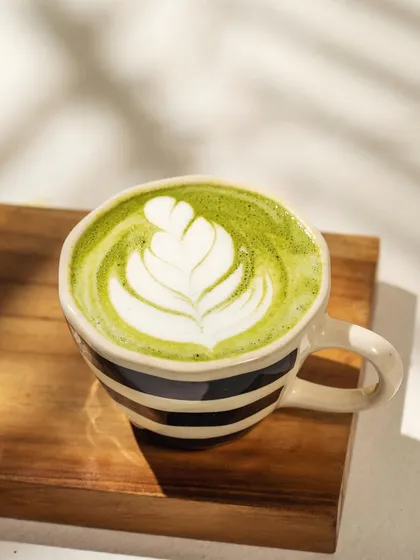 The beauty of a simple moment. The interplay of natural light, shadow, and delicate latte art makes this matcha shot feel both fresh and artistic, perfect for a modern cafe's aesthetic.