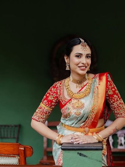A bride poses elegantly in a beautiful saree, her smile radiant against the green walls of our heritage suite.