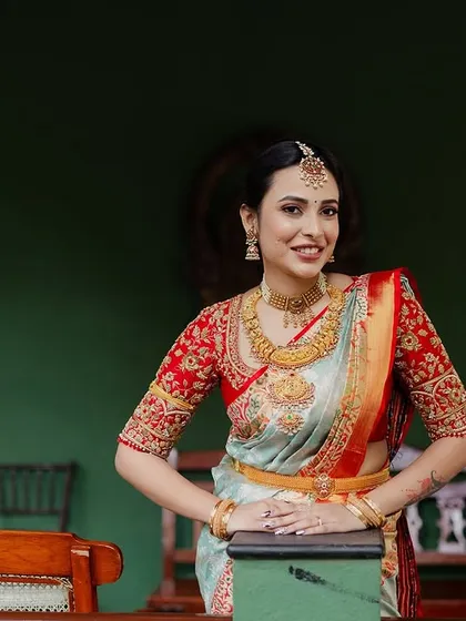 A bride poses on the verandah, her elegant saree and jewelry perfectly complementing the classic, heritage background.