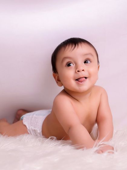 A happy baby lying on a soft fur rug, looking up with a sweet and playful expression. We focus on capturing your baby's personality in every shot.