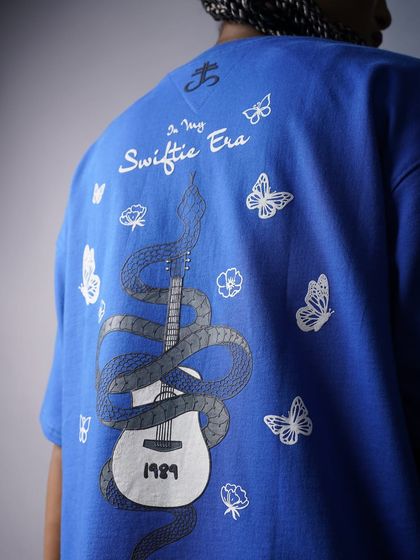 A shot focusing on the back of the blue 'Swiftie Era' t-shirt, showcasing the intricate guitar and snake graphic. This is perfect for highlighting unique design elements.