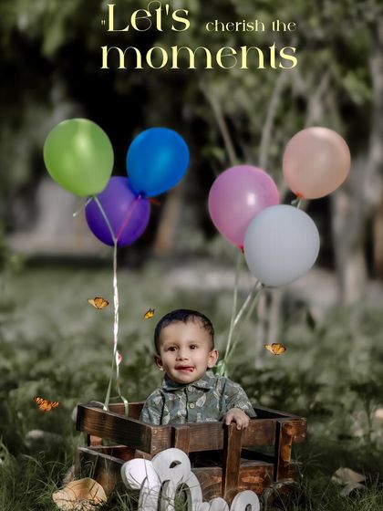 Let's cherish the moments. This happy boy is surrounded by balloons in a wooden cart during his outdoor first birthday photoshoot.