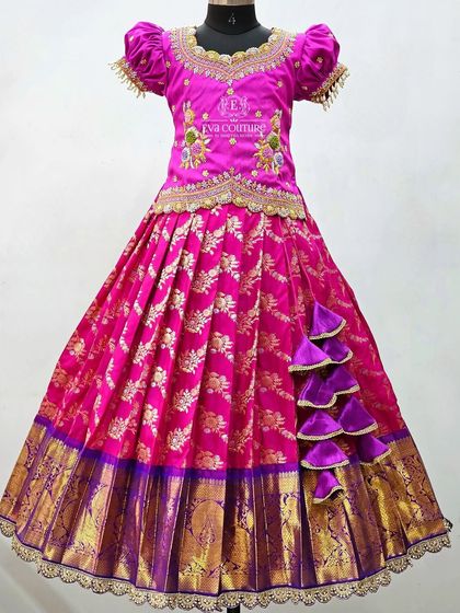 A magnificent pink and purple Banarasi lehenga. The blouse is heavily embroidered, and the skirt has a unique side cascade of tassels.
