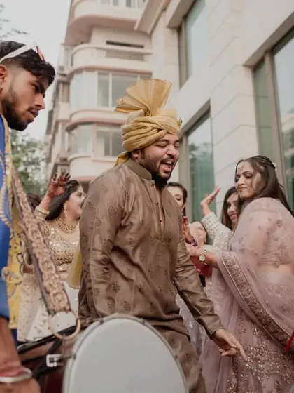 Guests and dhol players creating a vibrant, energetic atmosphere during the baraat procession.