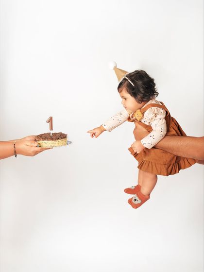 That first taste of birthday cake. A parent holds out the cake to the birthday girl in this creative and memorable shot.