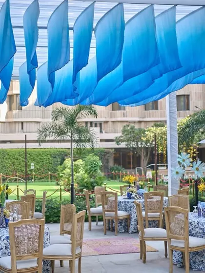 A wide view of the open garden dining area, with a canopy of flowing blue drapes creating a beautiful wave-like effect overhead.