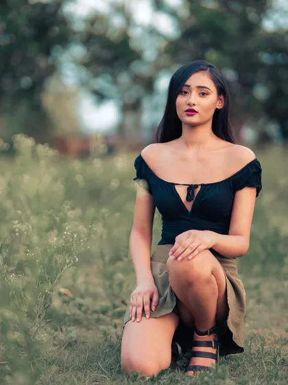 This kneeling pose feels grounded and connected to the earth. The green tones of the skirt and the field tie the whole image together.