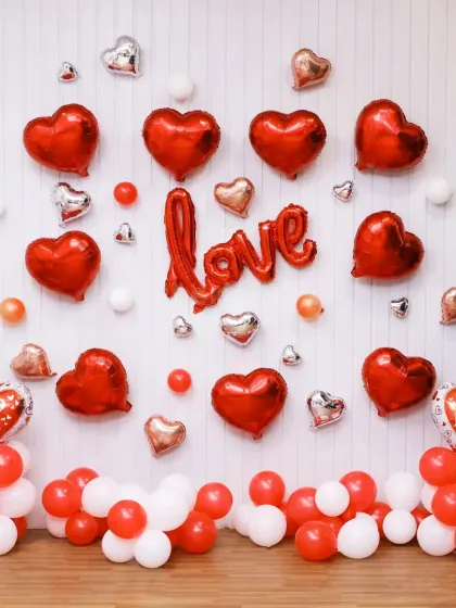 Another romantic setup with red heart-shaped foil balloons and a 'LOVE' sign. This is a classic and beautiful way to decorate for an anniversary or Valentine's Day.