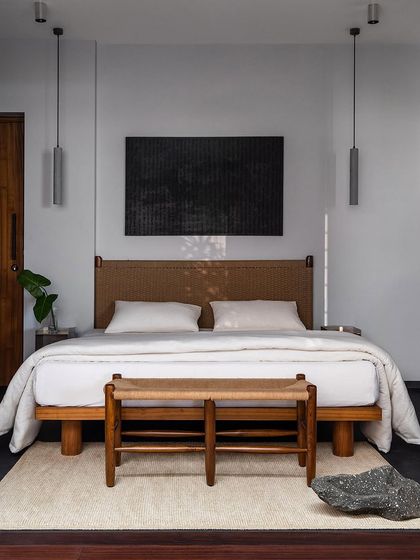 The master bedroom, designed with a focus on symmetry and asymmetry. The custom bed with its handwoven headboard is centered, while the surrounding elements create a balanced, dynamic composition.