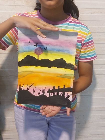 A student holding up her beautiful sunset landscape painting. The color gradient in the sky is just perfect. It’s wonderful to see their skills develop over time.