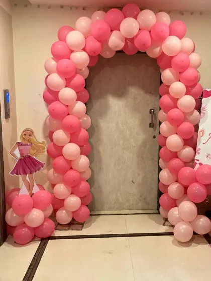 The entrance to the Barbie party, featuring a pink balloon arch and a Barbie cutout to welcome guests.